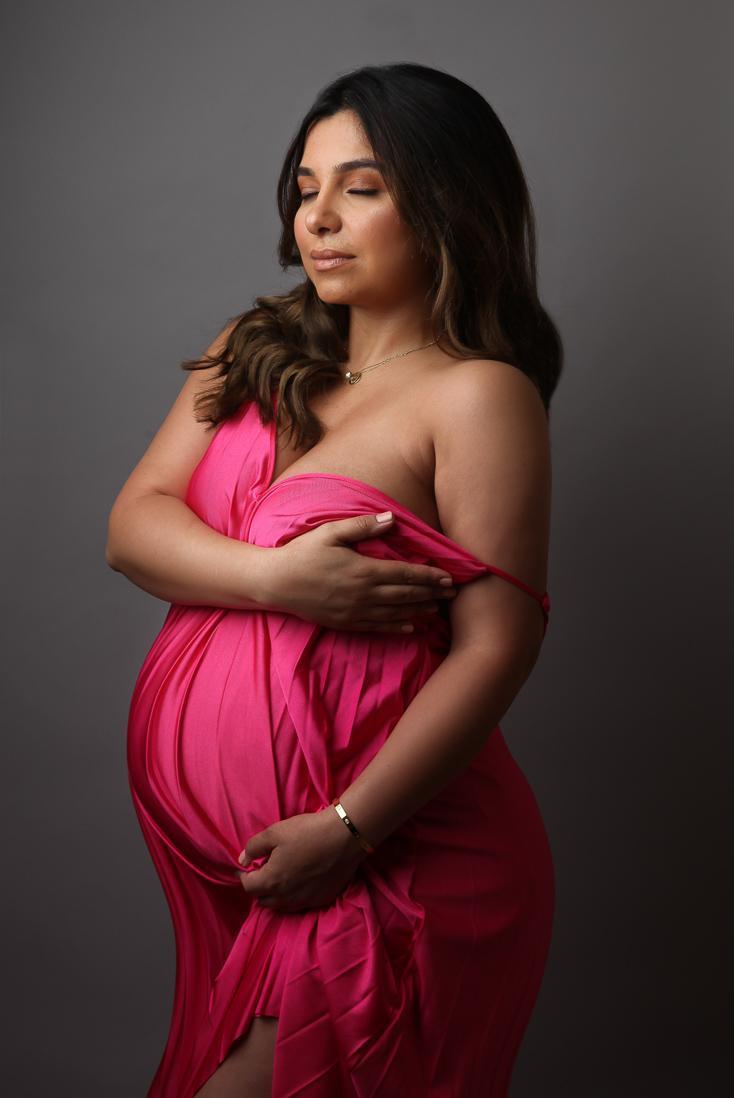 pregnant women in pink dress holding her bump