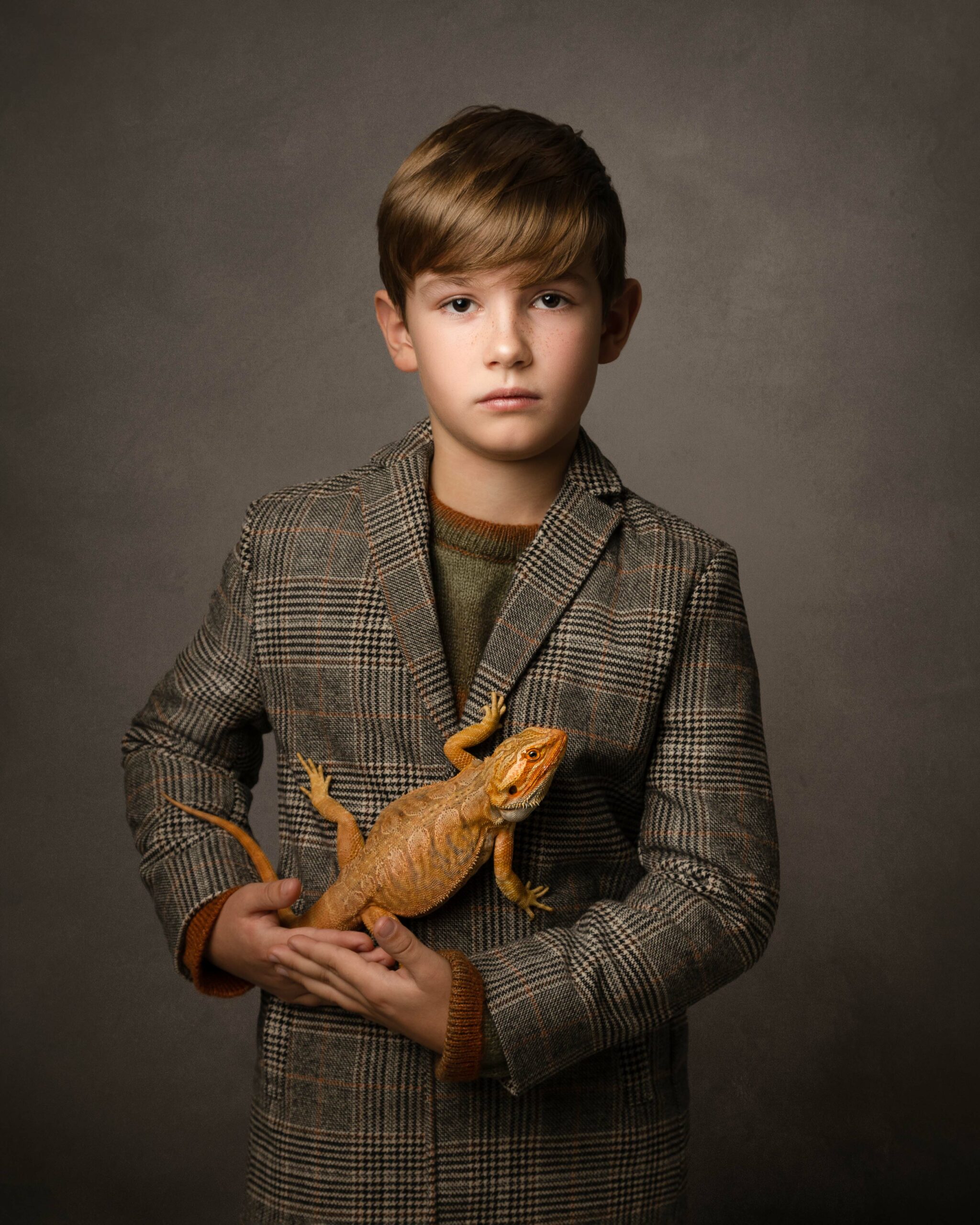 boy in checked jacket holding bearded dragon